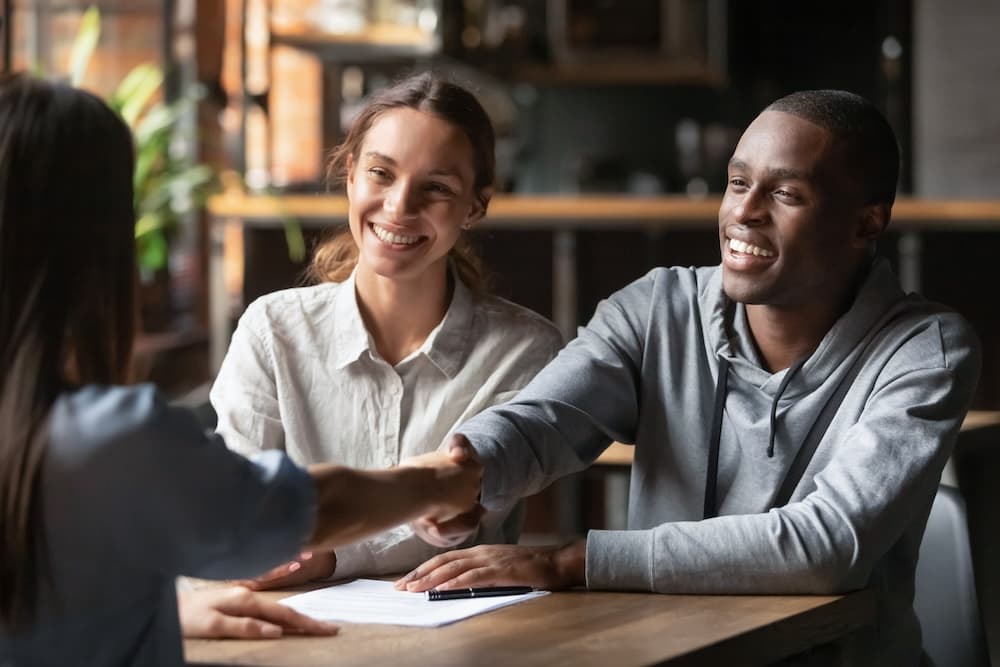 couple mixte en train de serrer la main a une autre personne