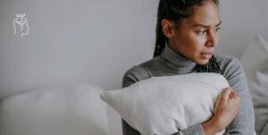 Jeune femme tenant un coussin dans ses bras paraissant angoissée