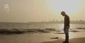 Jeune homme sur la plage au coucher du soleil
