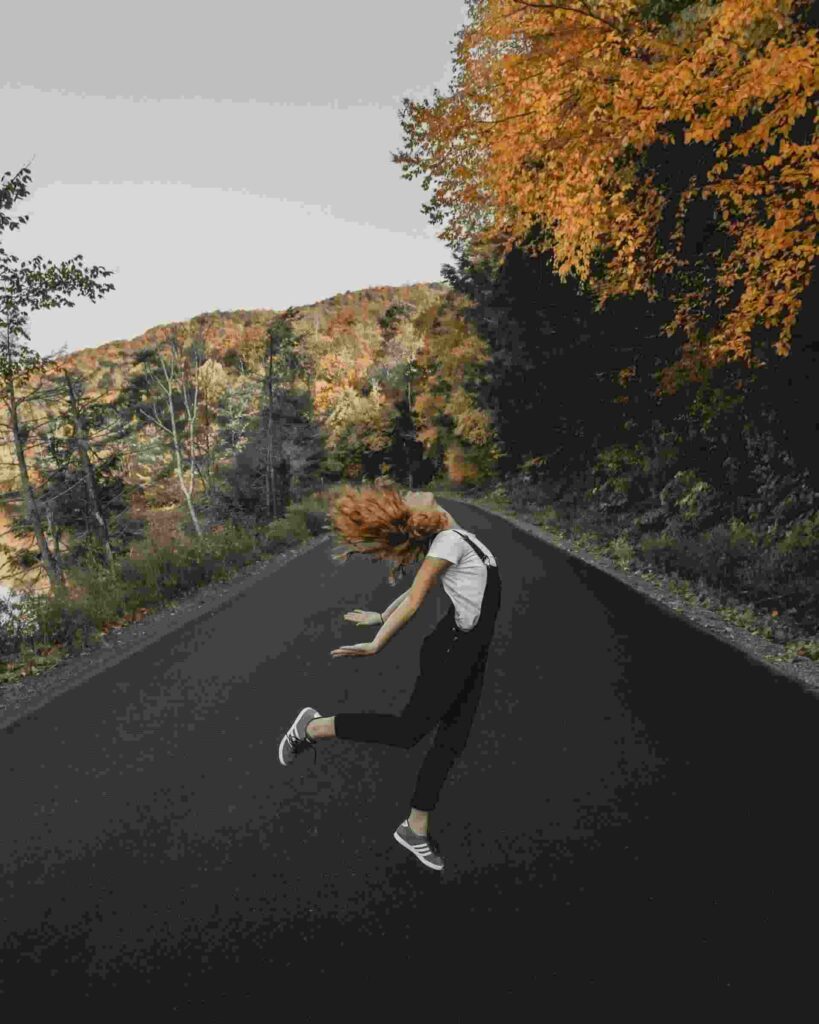 jeune femme heureuse en train de sauter au milieu d'une route