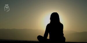 Jeune femme assise face au coucher du soleil