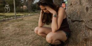Jeune femme accroupie qui se prend la tête dans ses mains