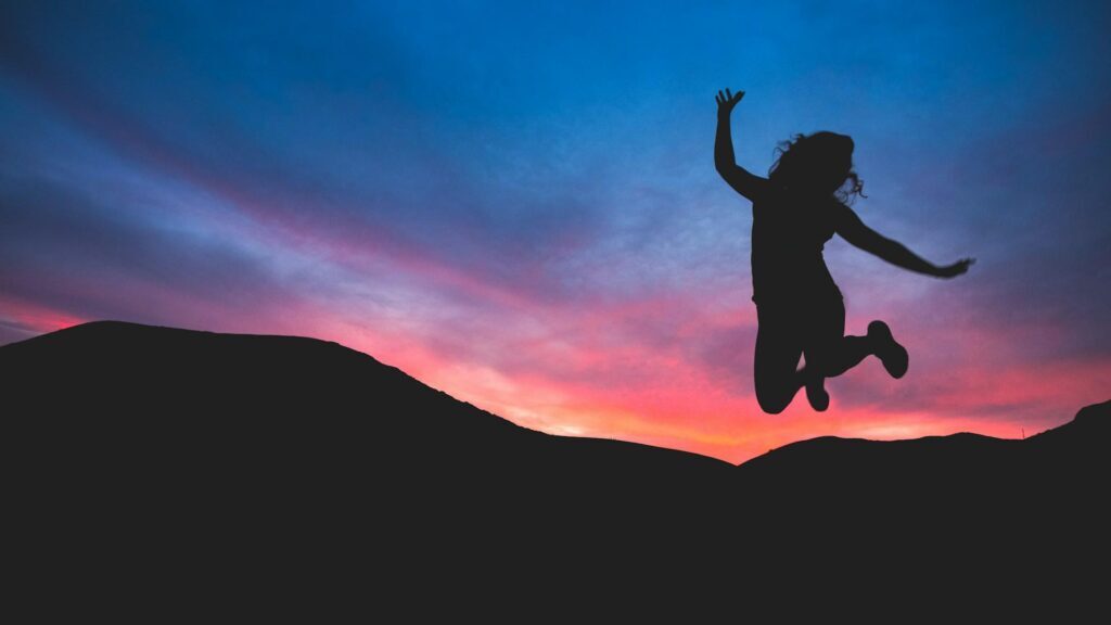 femme heureuse en train de sauter au coucher du soleil