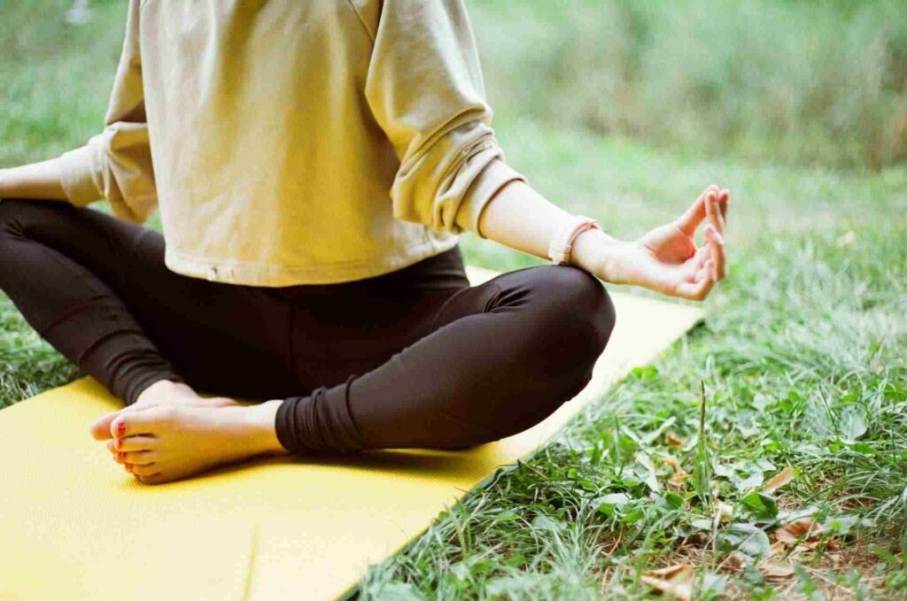 femme en train de méditer assise sur l'herbe