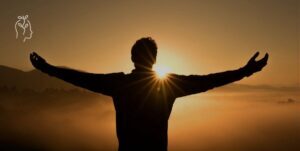 Homme qui ouvre les bras face au coucher de soleil