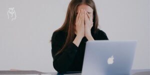 Femme devant son ordinateur portable qui prend son visage dans ses mains