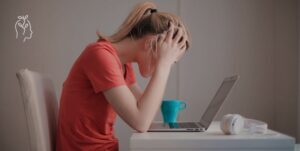 Femme qui se prend la tête dans ses mains devant son ordinateur portable
