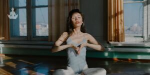 Jeune femme brune en train de méditer chez elle