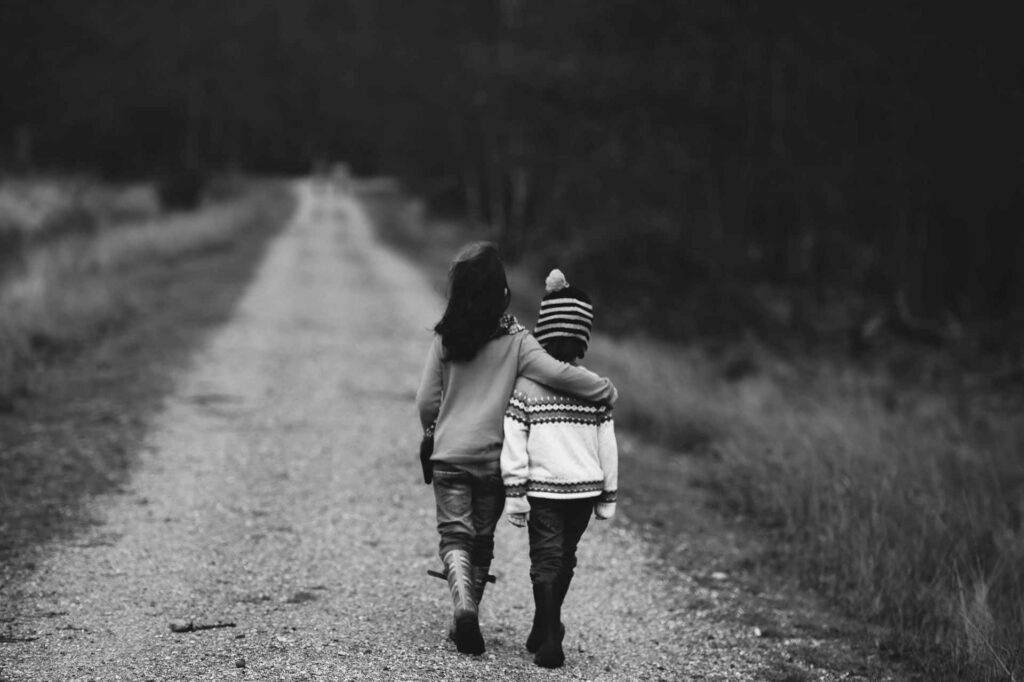 photo en noir et blanc de deux enfants se promenant en se tenant par les bras