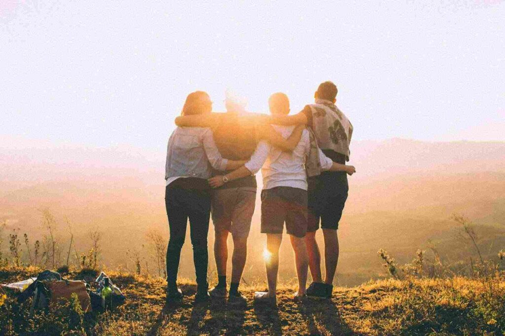 bande d'amis en train de se tenir par les bras face au coucher du soleil
